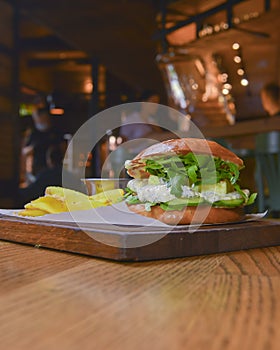 Delicious juicy chef cheeseburger served with fries on a rustic wooden board on a table in bar or restaurant