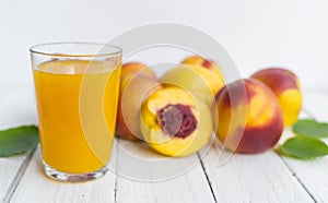 Delicious and juicy peach nectarina with glass of juice on white wooden table