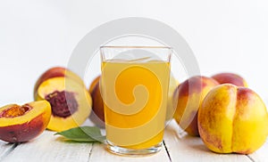 Delicious and juicy peach nectarina with glass of juice on white wooden table