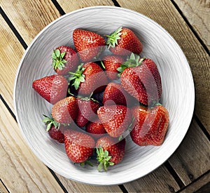 Delicious juicy strawberries on the plate with wooden background