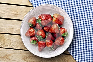 Delicious juicy strawberries on the plate with wooden background
