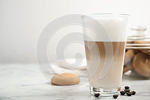 Delicious latte macchiato, cookies and coffee beans on white marble table, space for text