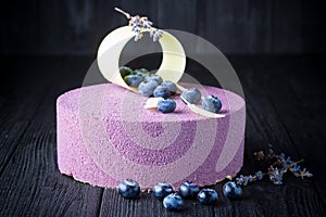 Delicious lavender cake with blueberries on wooden table