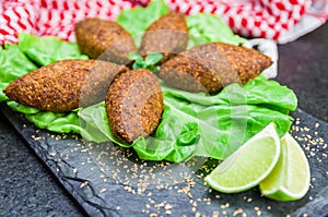 Delicious Lebanese  food, kibbeh kibe with sauces and lemon on black slate stone and granite background with traditional keffyeh