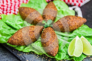 Delicious Lebanese  food, kibbeh kibe with sauces and lemon on black slate stone and granite background with traditional keffyeh