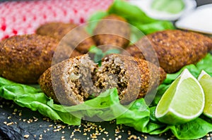 Delicious Lebanese  food, kibbeh kibe with sauces and lemon on black slate stone and granite background with traditional keffyeh