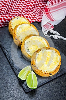 Delicious Lebanese food, sfiha au gratin with labneh and cheese on black slate stone background and traditional Lebanese keffiyeh