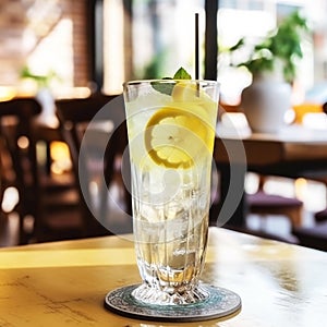 Delicious lemon drink, lemonade with lemon slices in a transparent glass dish on the table in a cafe