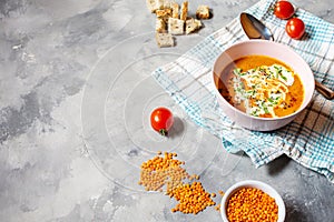 Delicious lentils soup with heavy cream on concrete table with red bell pepper, bread toasts.