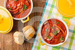 Delicious letcho with fresh vegetables, served in a yellow pot with the fresh bun