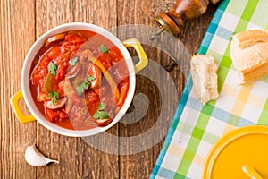 Delicious letcho with fresh vegetables, served in a yellow pot with the fresh bun