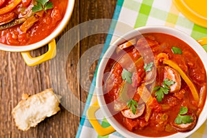 Delicious letcho with fresh vegetables, served in a yellow pot with the fresh bun