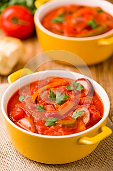 Delicious letcho with fresh vegetables, served in a yellow pot with the fresh bun