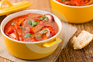 Delicious letcho with fresh vegetables, served in a yellow pot with the fresh bun