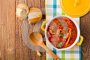 Delicious letcho with fresh vegetables, served in a yellow pot with the fresh bun