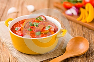 Delicious letcho with fresh vegetables, served in a yellow pot with the fresh bun