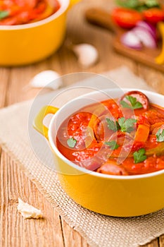 Delicious letcho with fresh vegetables, served in a yellow pot with the fresh bun