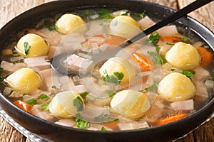 Delicious Liechtenstein cuisine soup with ham and cornmeal dumplings close-up in a plate. horizontal