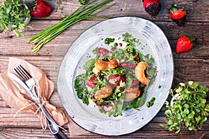 Delicious light salad with grilled shrimps, strawberries, arugula, parsley, spinach and scallion, sprinkled with fried sesame