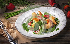 Delicious light salad with grilled shrimps, strawberries, arugula, parsley, spinach and scallion, sprinkled with fried sesame