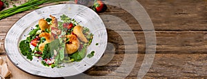 Delicious light salad with grilled shrimps, strawberries, arugula, parsley, spinach and scallion, sprinkled with fried sesame