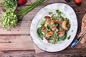 Delicious light salad with grilled shrimps, strawberries, arugula, parsley, spinach and scallion, sprinkled with fried sesame