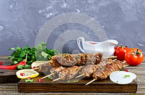 Delicious lula kebab on a wooden table. Chopped meat on wooden skewers, grilled.