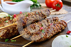 Delicious lula kebab on a wooden table. Chopped meat on wooden skewers, grilled.