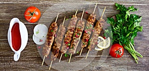 Delicious lula kebab on a wooden table. Chopped meat on wooden skewers, grilled. Eastern cuisine. Top view, flat lay.