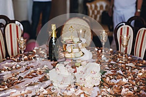 Delicious macarons on beautiful vintage stand and champagne glasses on table with gold confetti, bouquets, duck. Luxury catering