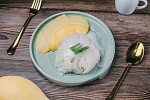 Delicious mango sticky rice serve with coconut milk on wooden table.