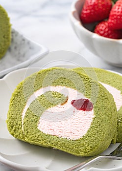 Delicious Matcha Swiss Roll Cake slices with strawberry cream on white background