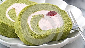 Delicious Matcha Swiss Roll Cake slices with strawberry cream on white background