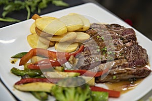 Delicious meal with steak strips, potato chips and grilled veggies on a white plate, tasty dish including several food groups
