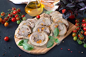Delicious meat rolls stuffed with vegetables with cherry tomatoes and basil. Festive dish