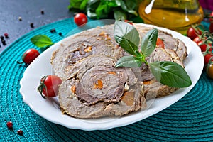 Delicious meat rolls stuffed with vegetables with cherry tomatoes and basil. Festive dish