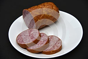 Delicious meat sausage on a white plate. Sliced ham. Slices of meat
