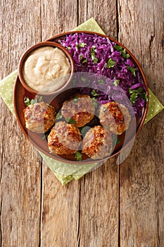 Delicious meatballs served with stewed red cabbage garnish and sauce close-up on the table. vertical top view