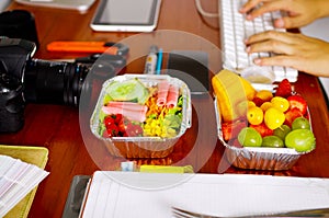 Delicious mediterranean-Style fresh salad with ham and fruit salad on aluminium box surrounded of office stuffs, break