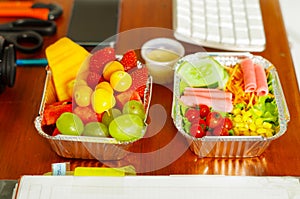 Delicious mediterranean-Style fresh salad with ham and fruit salad on aluminium box on wooden table