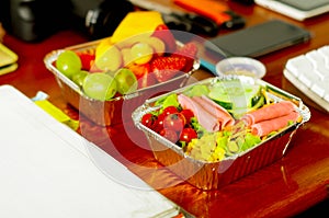 Delicious mediterranean-Style fresh salad with ham and fruit salad on aluminium box on wooden table