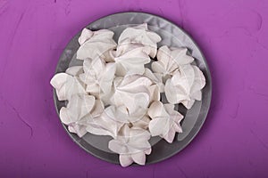 delicious meringue on gray plate on a purple background