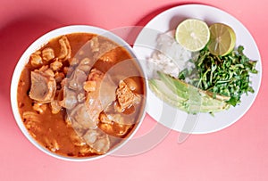 Delicious Mexican Menudo on a white plate accompanied by a dish with condiments on the side photo