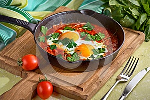 delicious middle east shakshuka - fried eggs, onion, bell pepper, tomatoes, chilli and spices in cast iron stewpan with