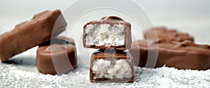 Delicious milk chocolate candy bars with coconut filling on grey table, closeup. Banner design