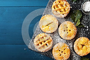 Delicious mini apple pies on blue background from above. Autumn pastry desserts.