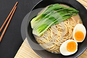 Delicious miso ramen noodles with egg in a bowl on a wood background.Top view