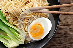 Delicious miso ramen noodles with egg in a bowl on a wood background.Top view