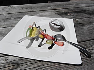 Delicious molten chocolate cake with fresh fruit and vanilla ice cream on rustic outdoor wooden table at summer