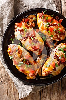 Delicious Monterey chicken breast baked with cheese, bacon, tomatoes and barbecue sauce close-up. Vertical top view